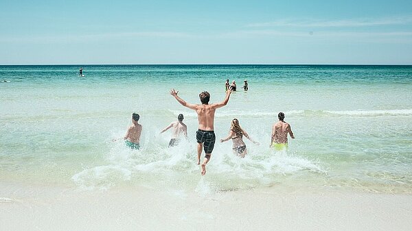 Personen planschen im Meer