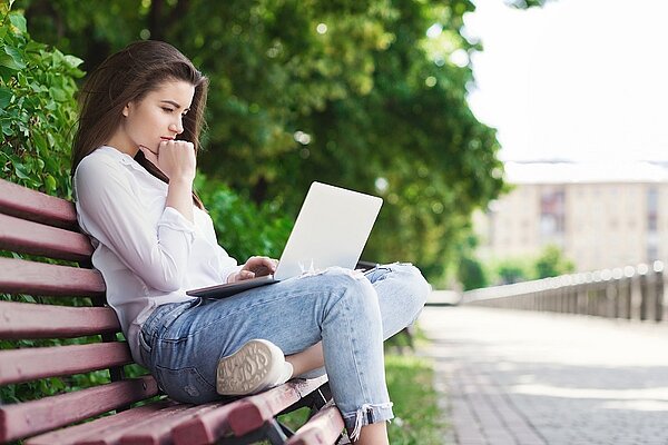 Frau auf Parkbank am Laptop